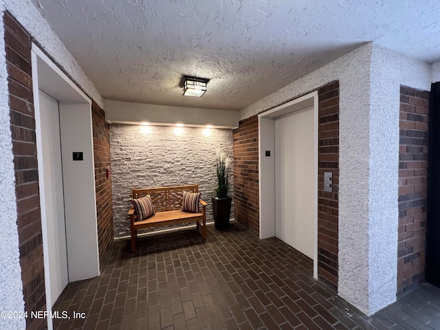 corridor featuring a textured ceiling and elevator