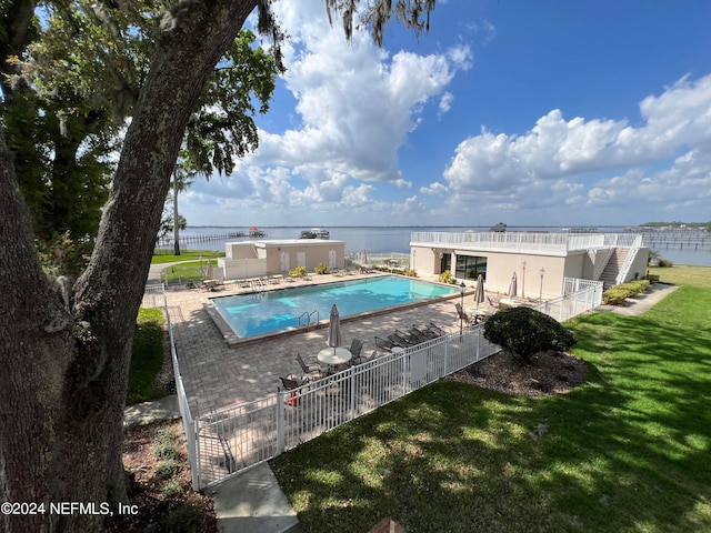 view of pool featuring a water view, a yard, and a patio area