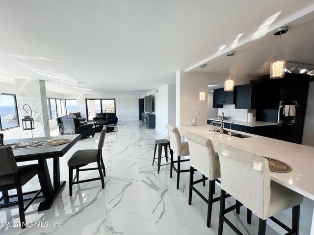 kitchen with pendant lighting, sink, kitchen peninsula, black fridge with ice dispenser, and a breakfast bar area