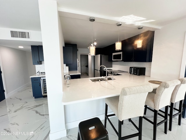 kitchen featuring blue cabinets, sink, kitchen peninsula, stainless steel appliances, and a kitchen bar