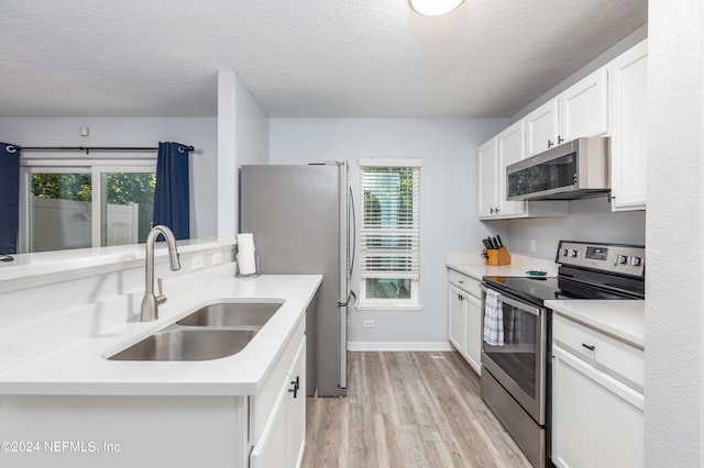 kitchen with stainless steel appliances, light wood-type flooring, sink, and a healthy amount of sunlight