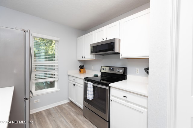 kitchen with appliances with stainless steel finishes, light wood-type flooring, and white cabinetry