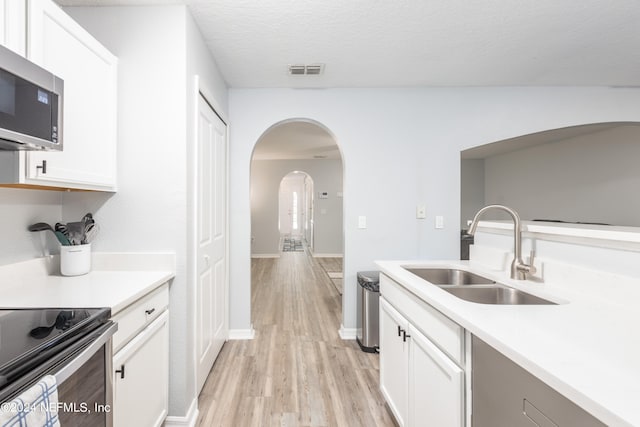 kitchen with white cabinets, light hardwood / wood-style flooring, and sink