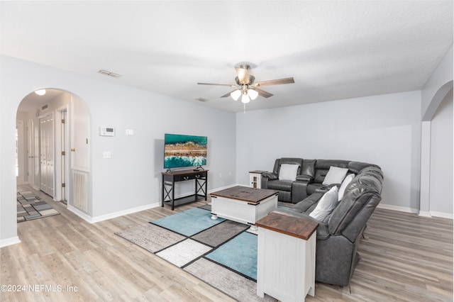 living room with ceiling fan, hardwood / wood-style flooring, and a textured ceiling