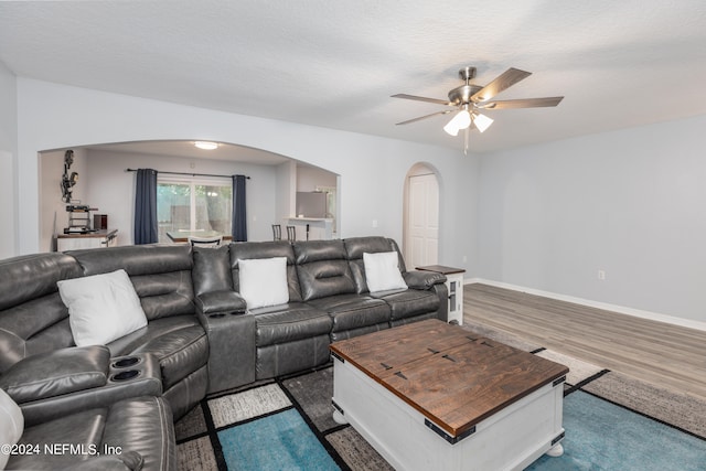 living room with a textured ceiling, dark hardwood / wood-style flooring, and ceiling fan