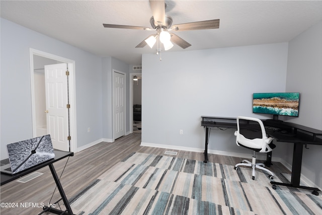 home office with wood-type flooring, ceiling fan, and a textured ceiling