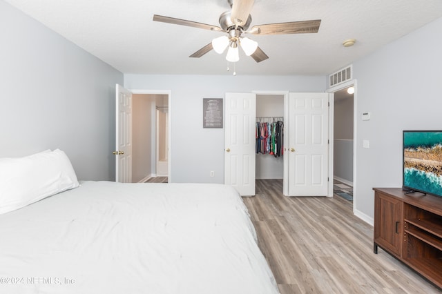 bedroom featuring a closet, a textured ceiling, light hardwood / wood-style flooring, a spacious closet, and ceiling fan