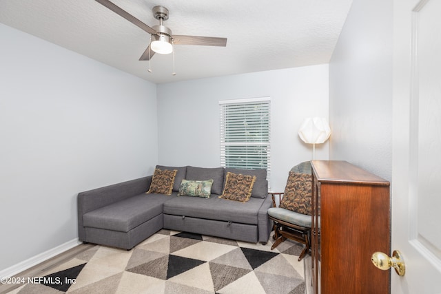 living room featuring light wood-type flooring, ceiling fan, and a textured ceiling