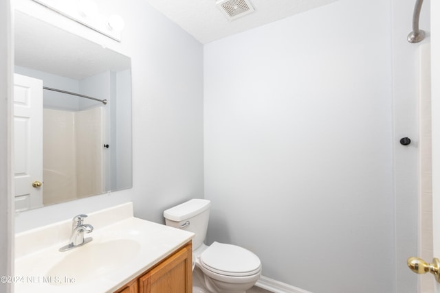 bathroom with a textured ceiling, vanity, toilet, and walk in shower