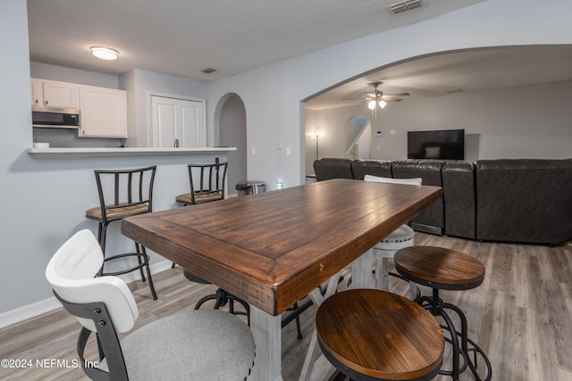 dining room with a textured ceiling, light hardwood / wood-style floors, and ceiling fan