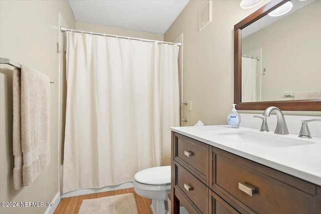 bathroom with curtained shower, vanity, a textured ceiling, hardwood / wood-style flooring, and toilet