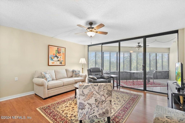 living room featuring wood-type flooring, ceiling fan, plenty of natural light, and expansive windows