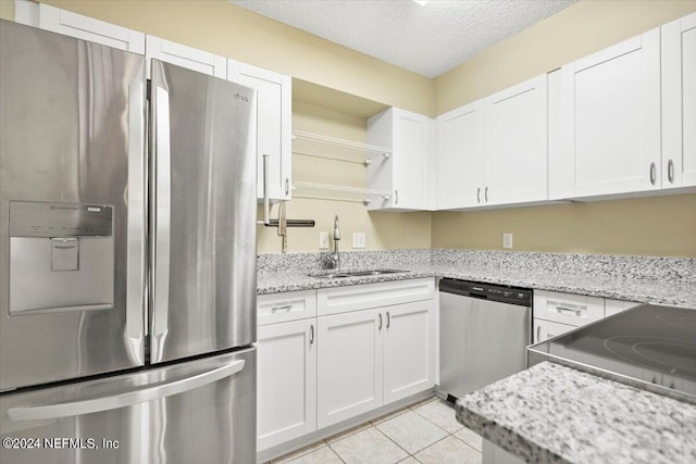 kitchen with light stone counters, white cabinets, stainless steel appliances, a textured ceiling, and sink