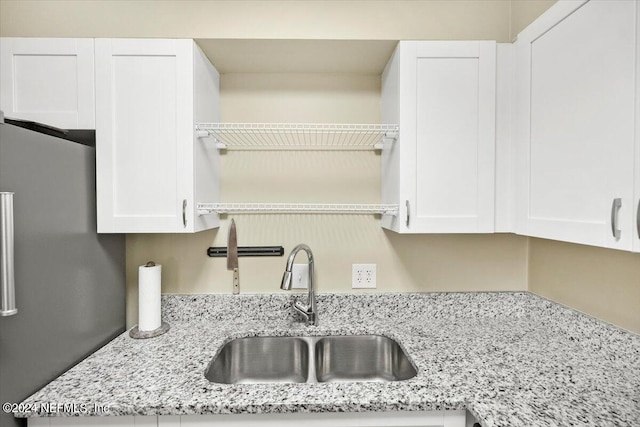 kitchen with stainless steel fridge, sink, and white cabinetry