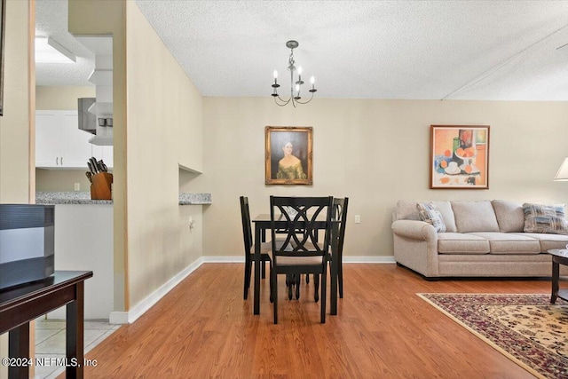 dining room featuring light wood-type flooring, a chandelier, and a textured ceiling