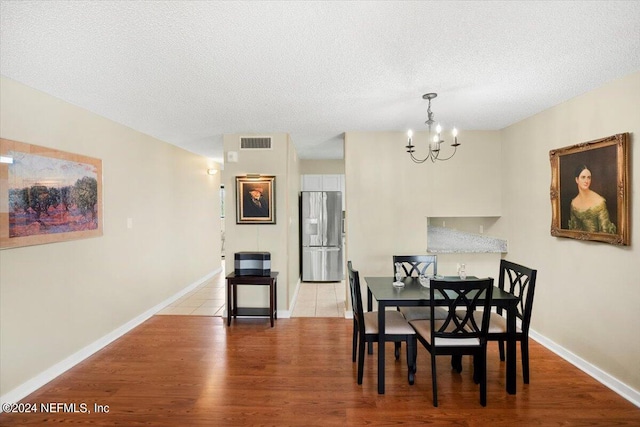 dining room featuring an inviting chandelier, light hardwood / wood-style flooring, and a textured ceiling