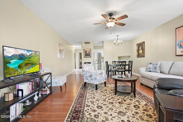 living room with wood-type flooring, a textured ceiling, and ceiling fan with notable chandelier