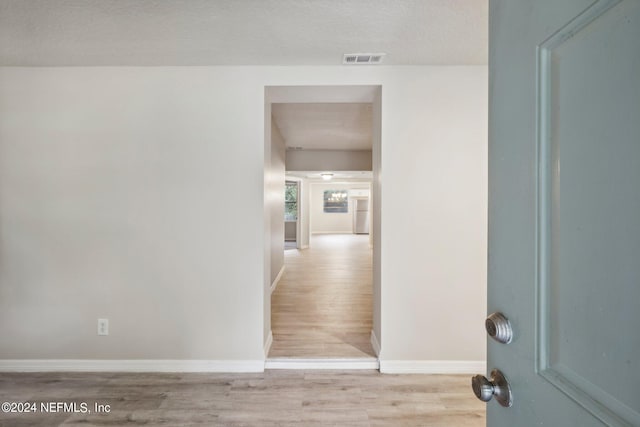 hall featuring a textured ceiling and light wood-type flooring