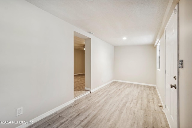 spare room with a textured ceiling and light wood-type flooring