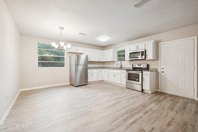 kitchen featuring sink, white cabinetry, hanging light fixtures, and stainless steel appliances