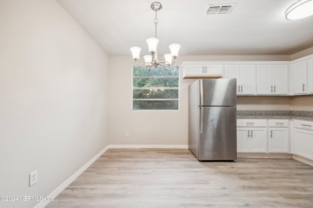 kitchen with stainless steel fridge, white cabinets, hanging light fixtures, a chandelier, and light hardwood / wood-style flooring