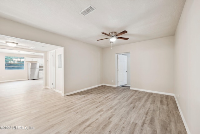 unfurnished room with a textured ceiling, light hardwood / wood-style floors, and ceiling fan