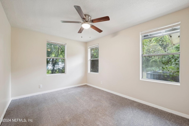 carpeted spare room featuring a textured ceiling, a healthy amount of sunlight, and ceiling fan