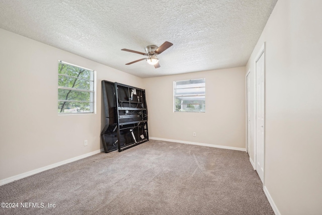 unfurnished bedroom featuring a textured ceiling, carpet floors, and ceiling fan