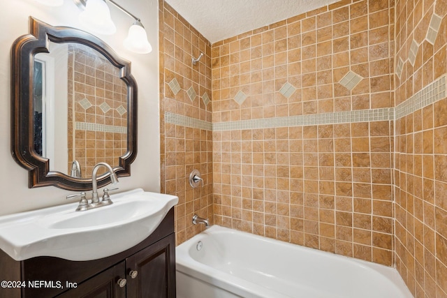 bathroom featuring vanity, tiled shower / bath, and a textured ceiling