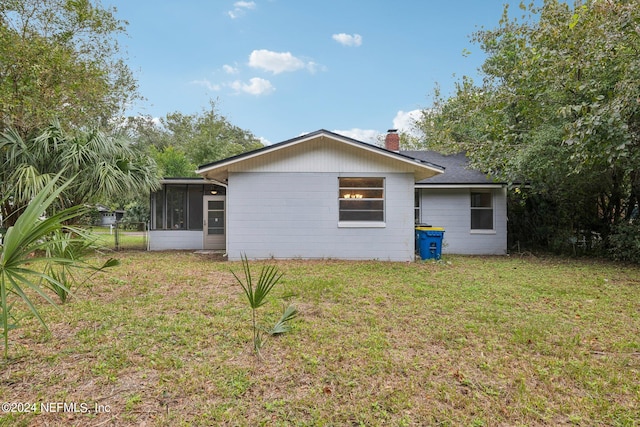 rear view of property featuring a sunroom and a lawn