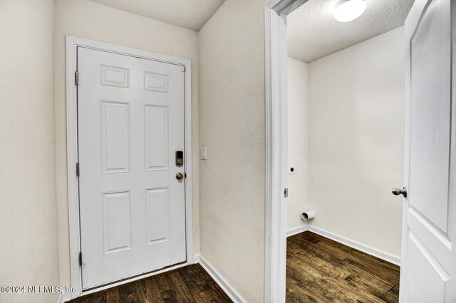 doorway with a textured ceiling and dark wood-type flooring