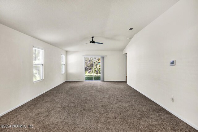 empty room with carpet floors, vaulted ceiling, and ceiling fan