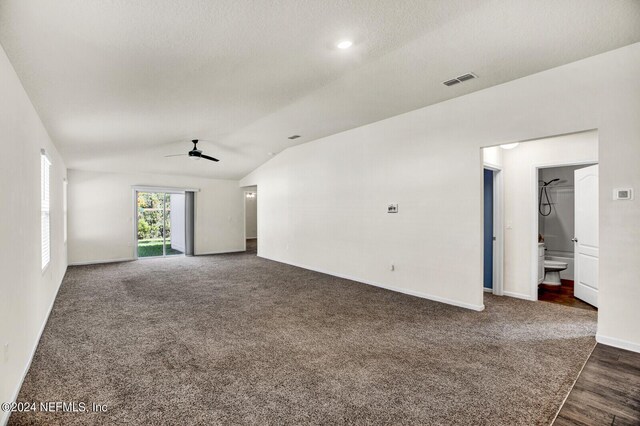 empty room with a textured ceiling, dark hardwood / wood-style floors, vaulted ceiling, and ceiling fan