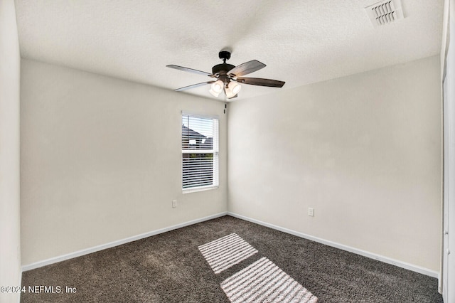 spare room with dark carpet and a textured ceiling