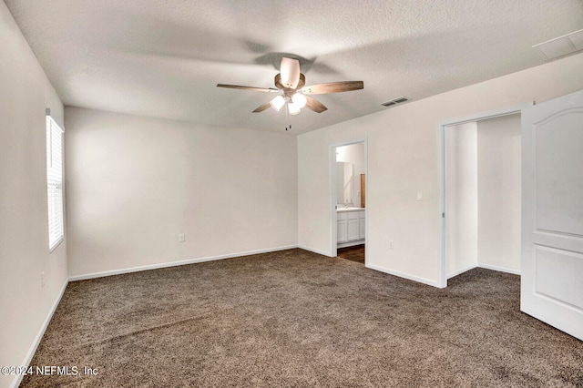 unfurnished bedroom featuring dark colored carpet, ceiling fan, a textured ceiling, and ensuite bath