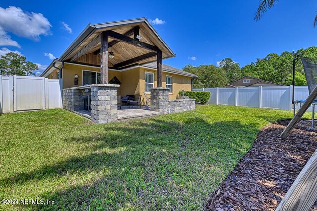 back of house featuring ceiling fan, a lawn, and a patio