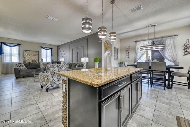 kitchen with light stone counters, a center island, plenty of natural light, and hanging light fixtures