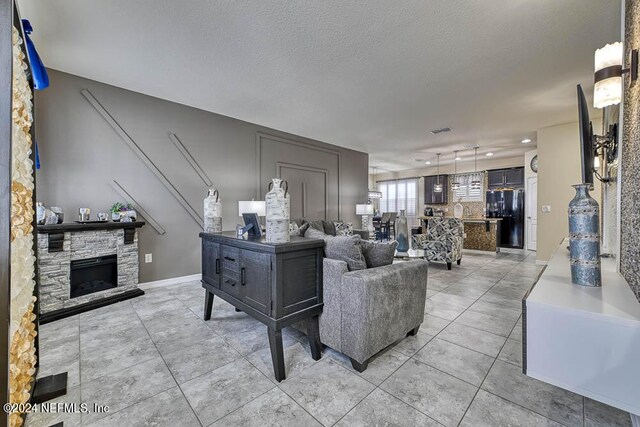 living room featuring a textured ceiling, a fireplace, and light tile patterned flooring