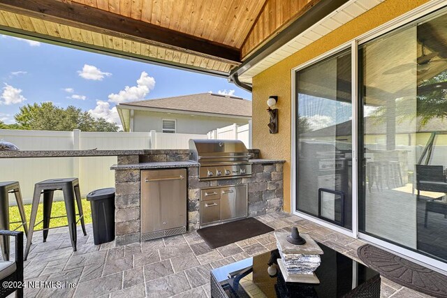 view of patio with an outdoor kitchen and a grill