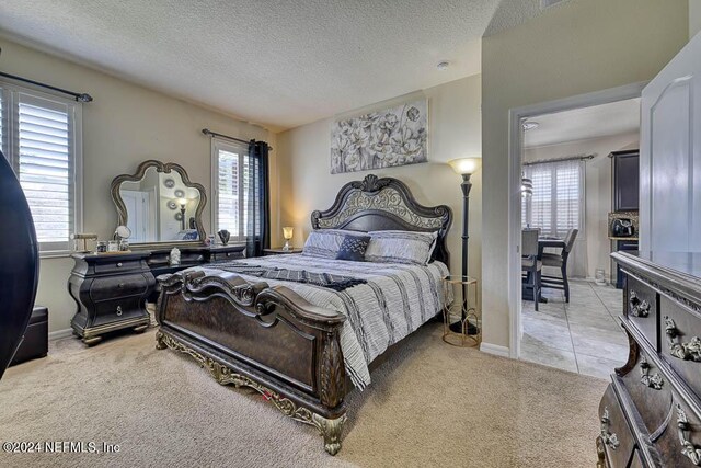 carpeted bedroom with a textured ceiling and multiple windows