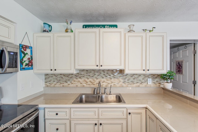 kitchen featuring backsplash, range, a textured ceiling, and sink