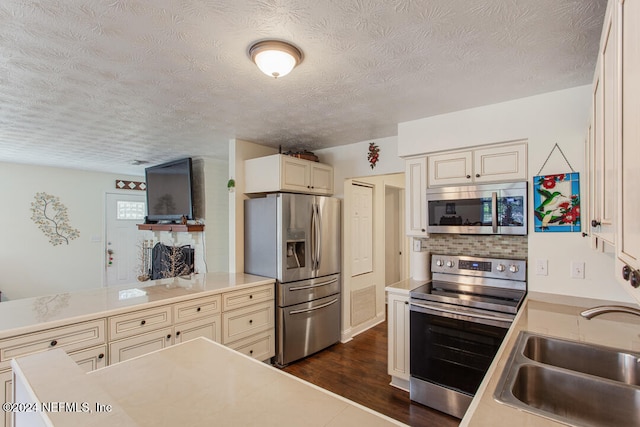 kitchen with stainless steel appliances, a textured ceiling, sink, and dark hardwood / wood-style flooring