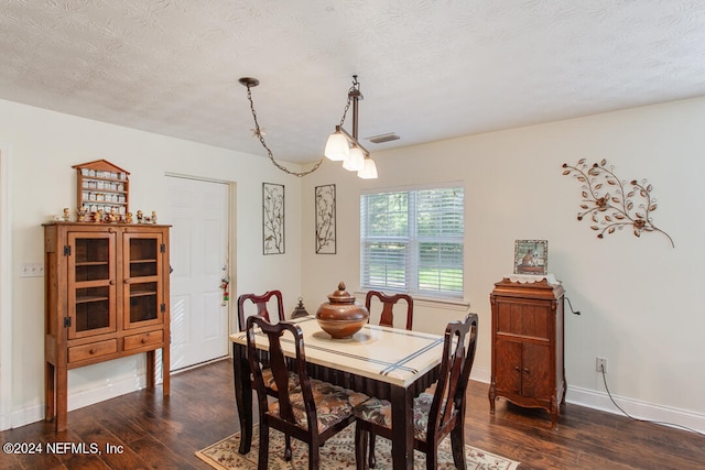 dining room with a textured ceiling and dark hardwood / wood-style flooring