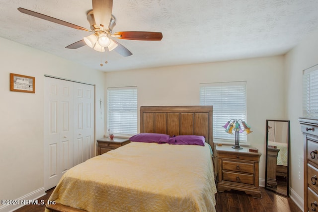 bedroom with a closet, ceiling fan, dark wood-type flooring, and a textured ceiling