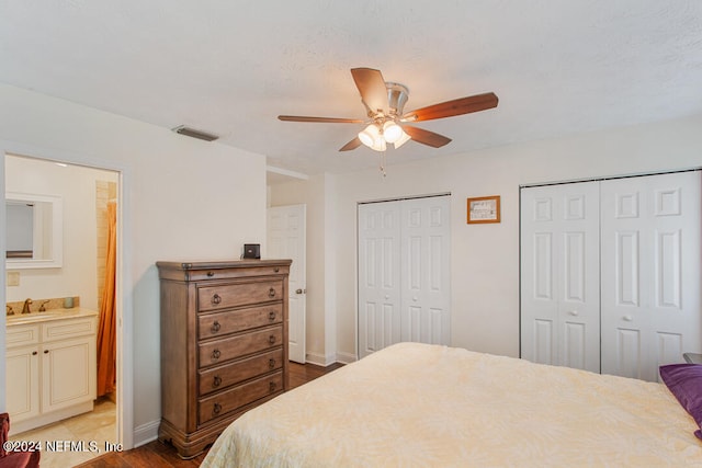 bedroom with ceiling fan, multiple closets, light hardwood / wood-style floors, ensuite bath, and sink