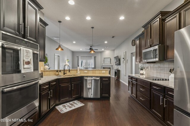 kitchen featuring ceiling fan, sink, stainless steel appliances, dark wood-type flooring, and pendant lighting