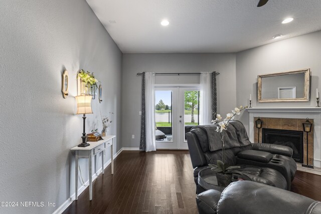 living room with dark hardwood / wood-style floors, a tile fireplace, and french doors