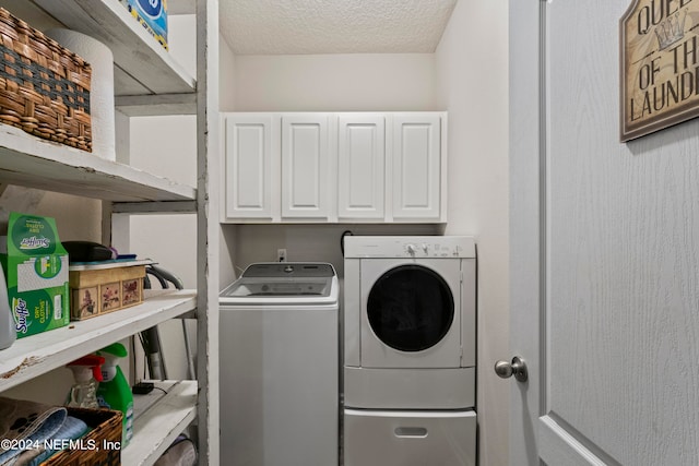 washroom featuring washer and clothes dryer, cabinets, and a textured ceiling