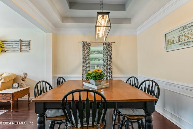 dining room with dark hardwood / wood-style flooring, a tray ceiling, and crown molding