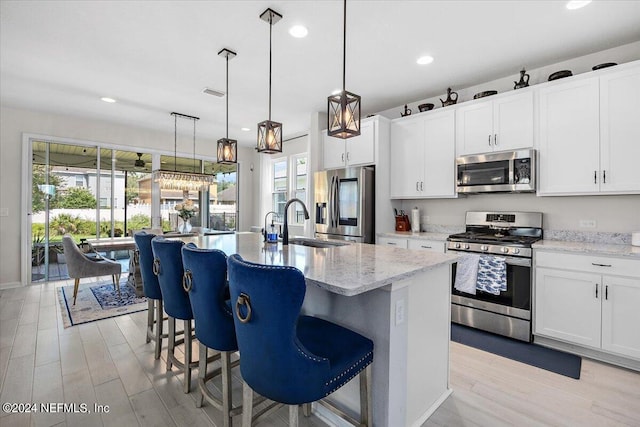 kitchen featuring appliances with stainless steel finishes, a center island with sink, light hardwood / wood-style floors, and plenty of natural light